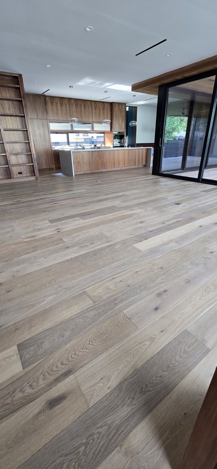 Light wood flooring across a large open-plan living room and kitchen