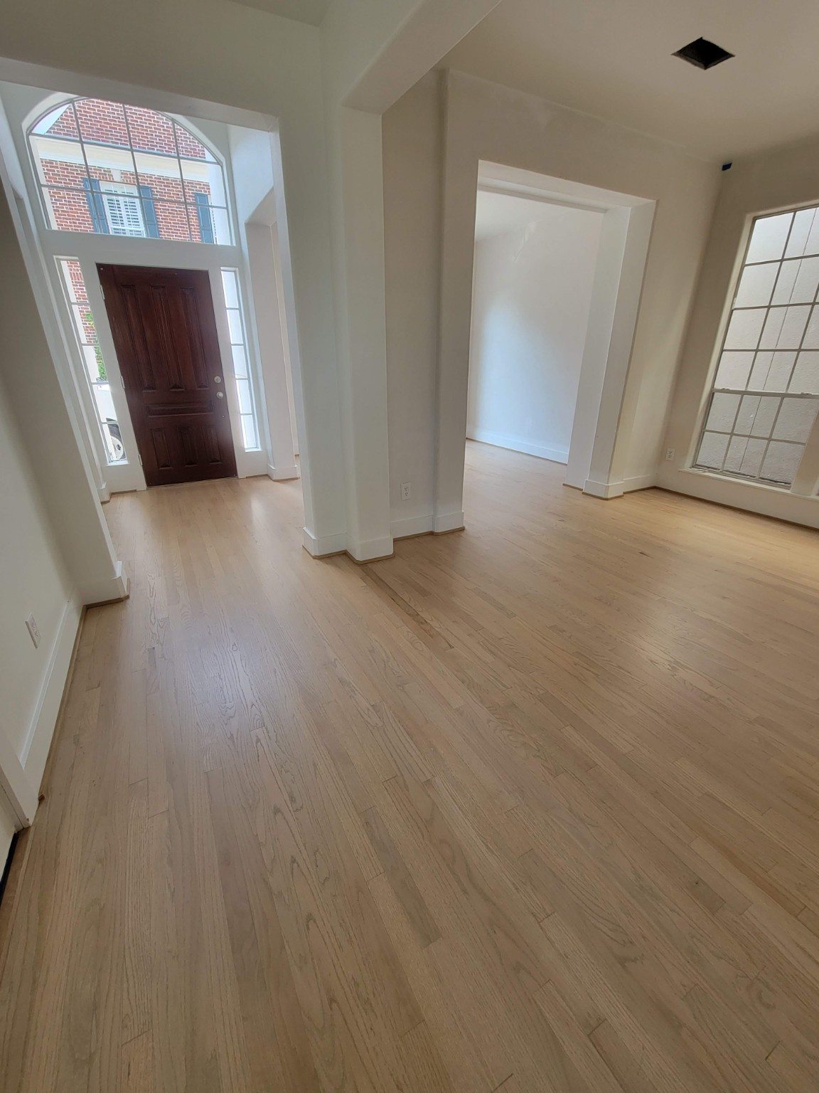 Light wood flooring across an entry and adjoining room