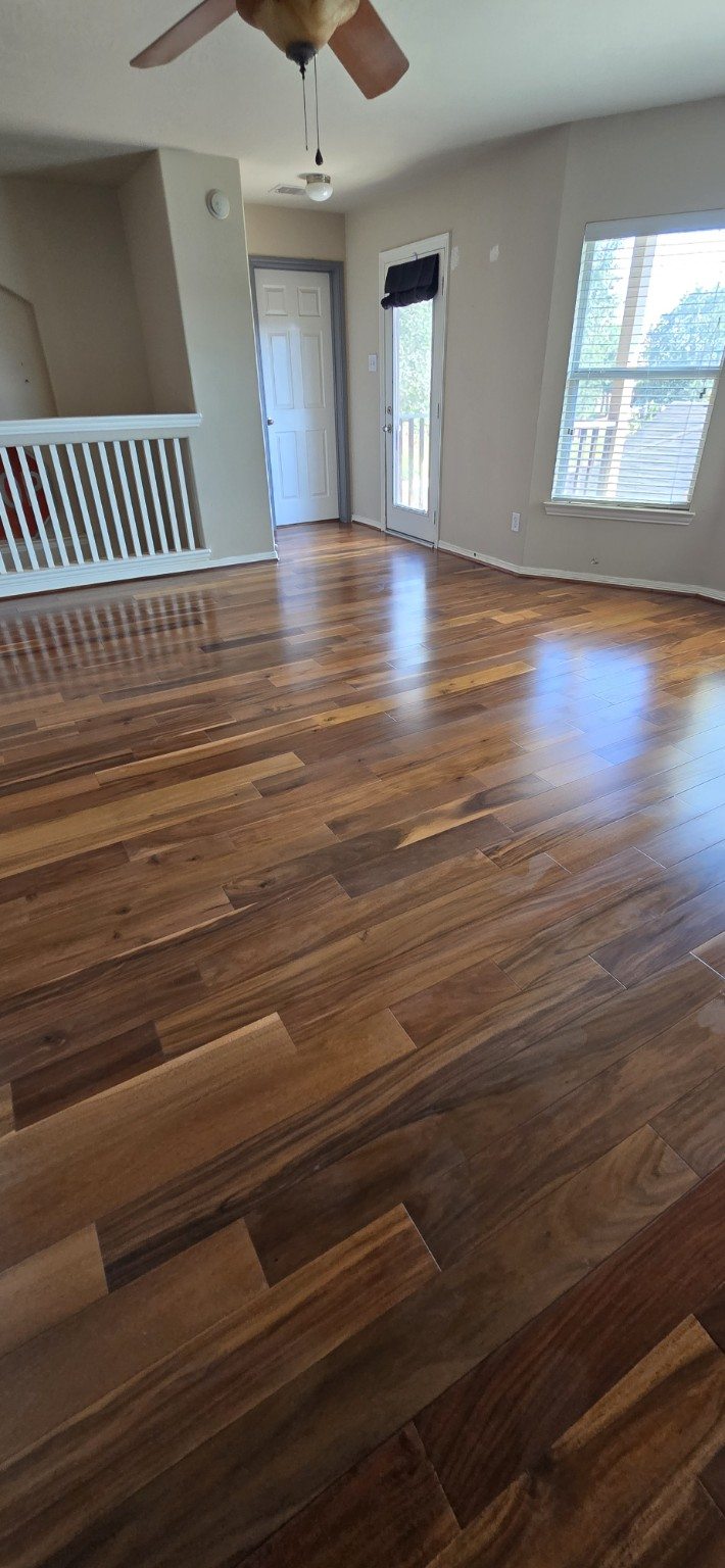 Brown wood floor beside white railing and windows