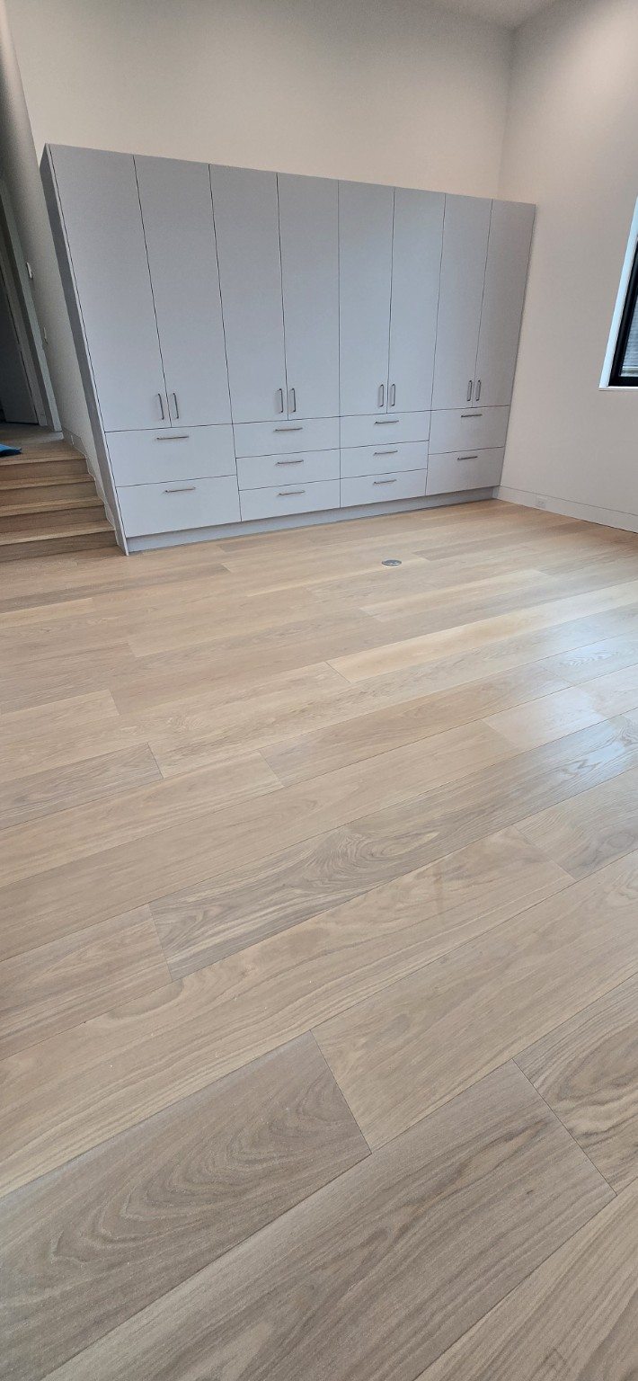 Pale natural wood floor in a bright room with built-in cabinets